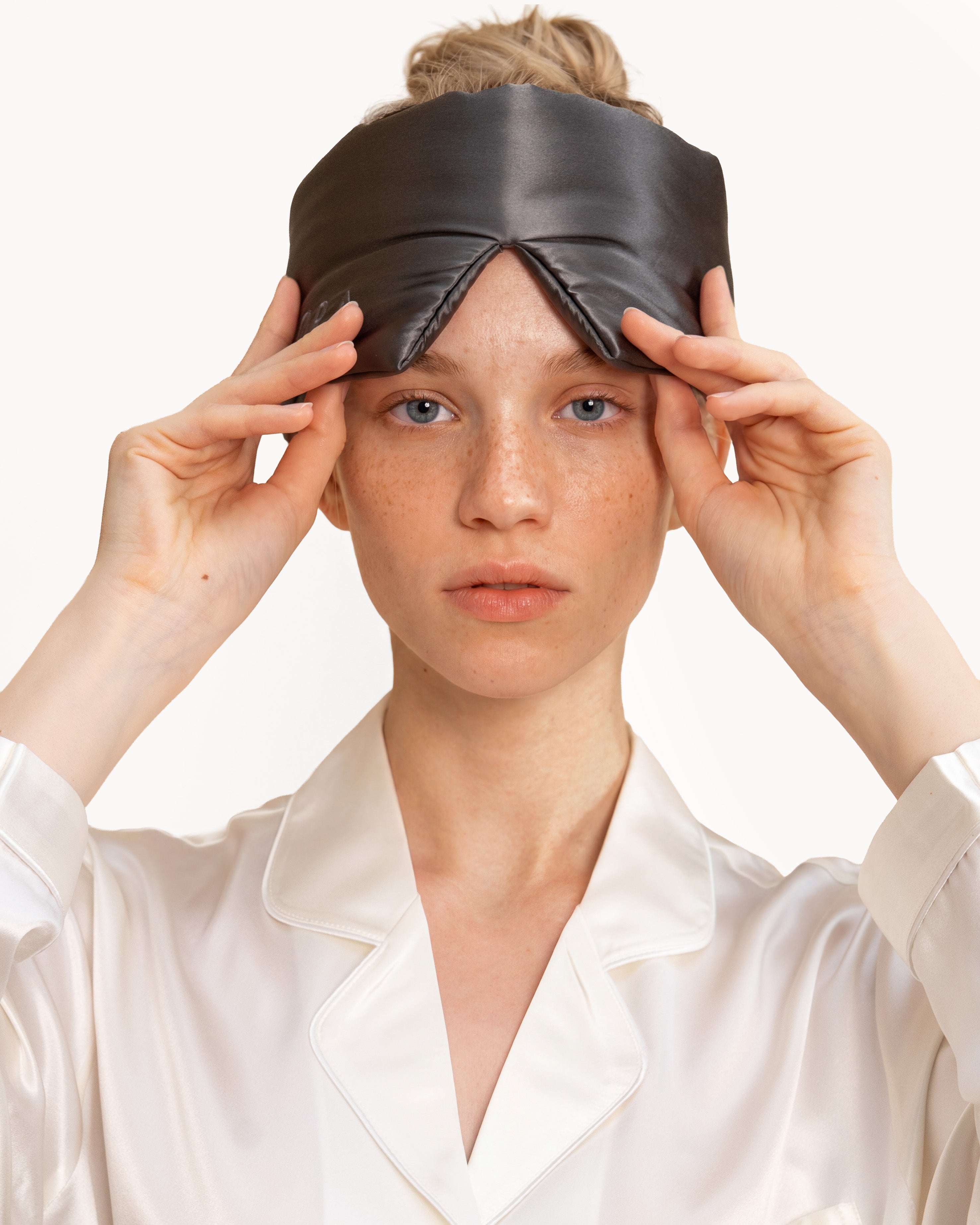 Model wearing a Dark Brown NORA silk sleep mask on her forehead, handcrafted with real silk mulberry silk fabric for hair protection.